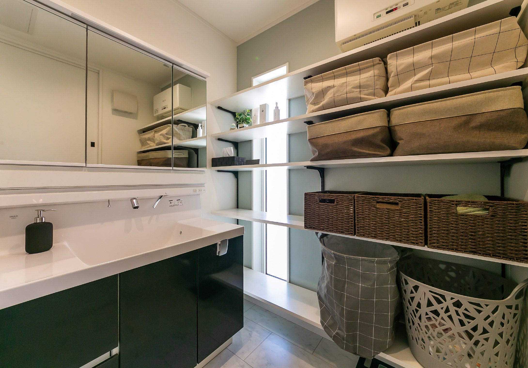 ワイドな洗面化粧台を設置した洗面室。タオル類などの収納スペースも豊富に設けられている。