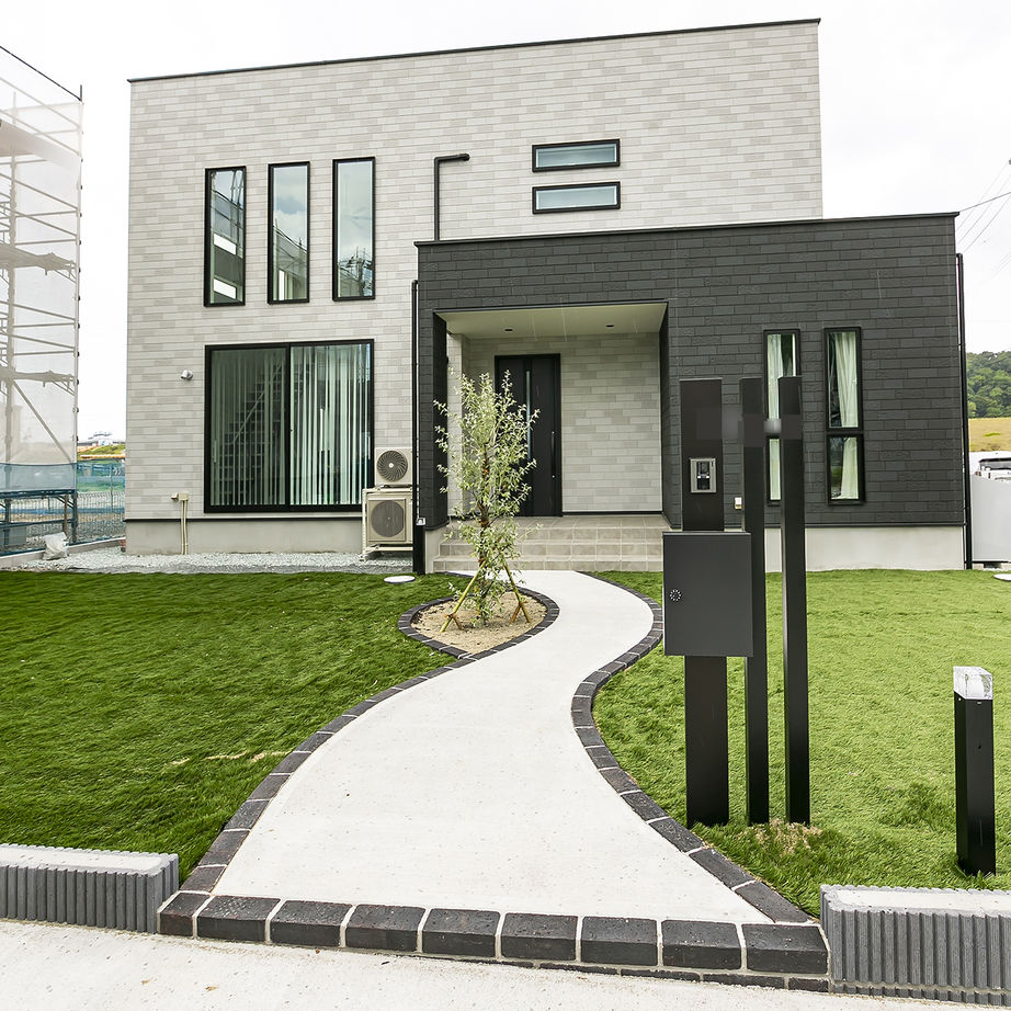 オフホワイトとブラックのコントラストがスタイリッシュな雰囲気を漂わせる外観。緩やかな曲線のアプローチがゆとりを感じさせる