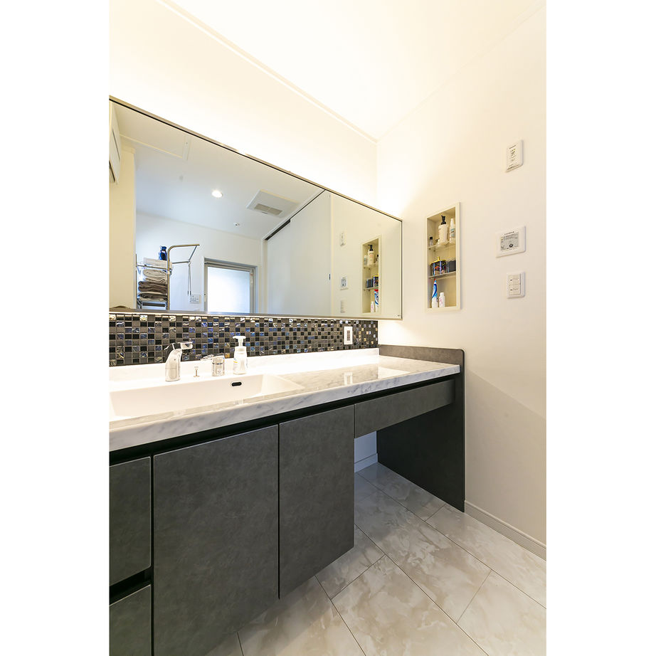 機能的でデザインも美しい洗面化粧台。鏡との間のタイルも色や柄にこだわって選んだ